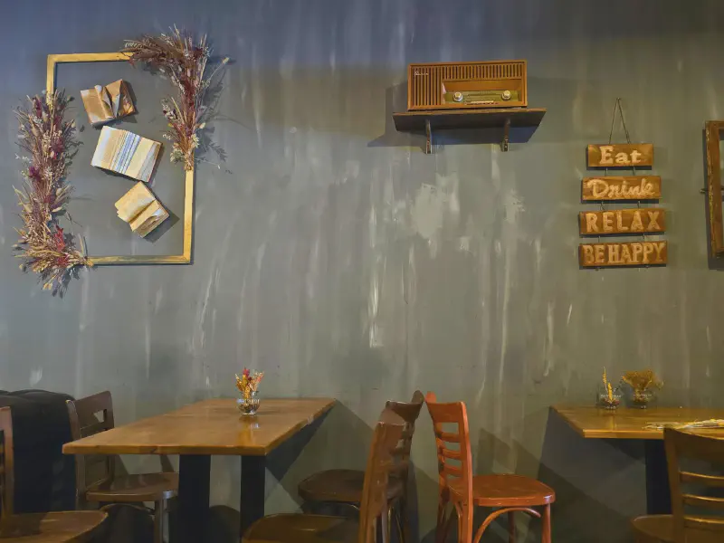 Café-Innenraum mit Holztischen und Eat-Drink-Relax-Schild