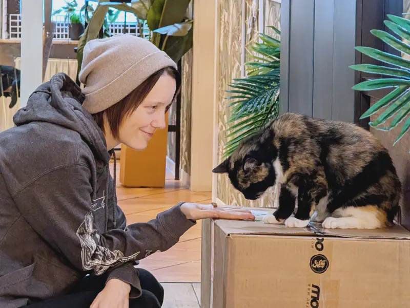 Gina füttert eine Katze mit einem Leckerli