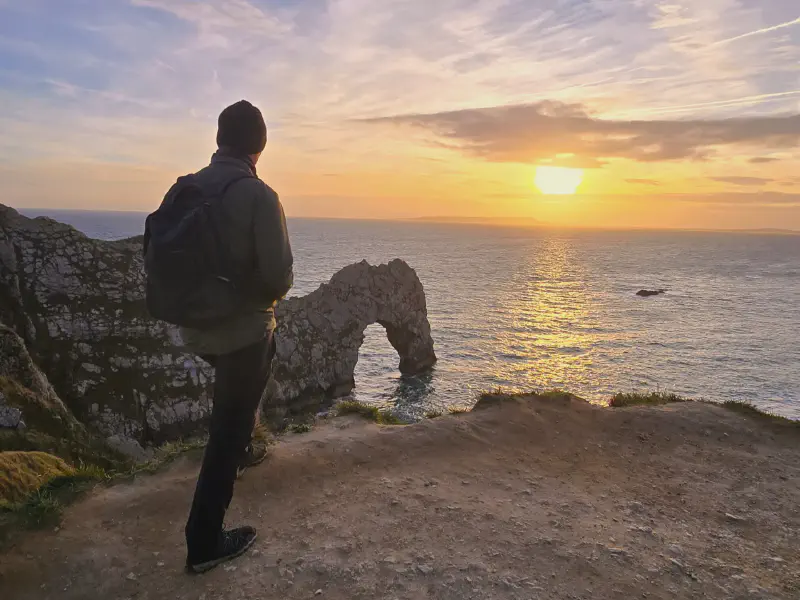 Oli schaut bei Sonnenuntergang auf die Durdle Door
