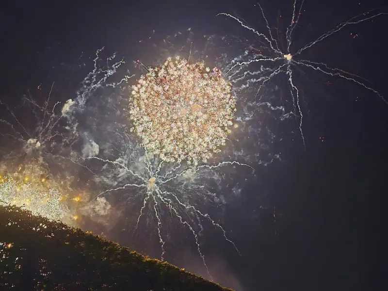 Riesige weiße Feuerwerksblüte mit langen Leuchtspuren