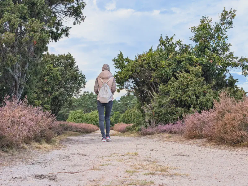 Gina läuft mit Rucksack über den Sandweg