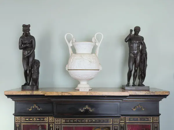 Two statues with a vase in the middle